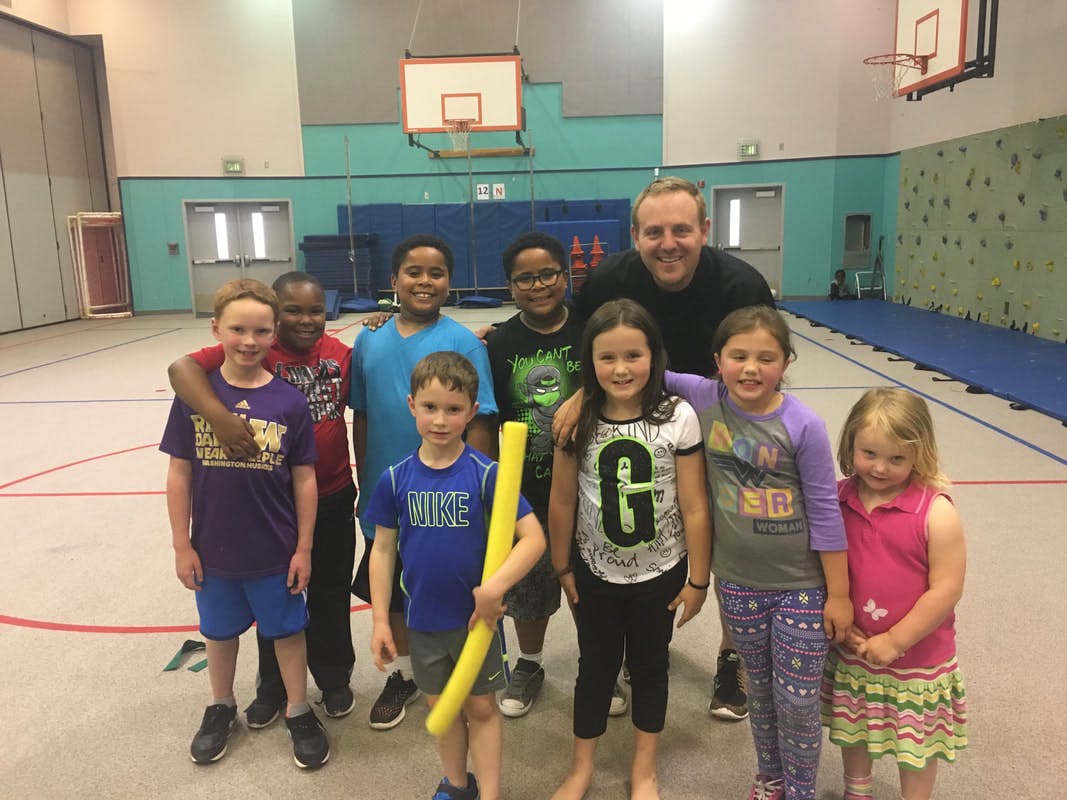 Adult and children posing for a photo in a gym