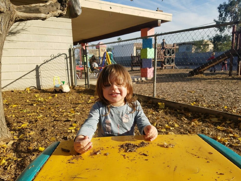 Child sitting at a yellow table outdoors