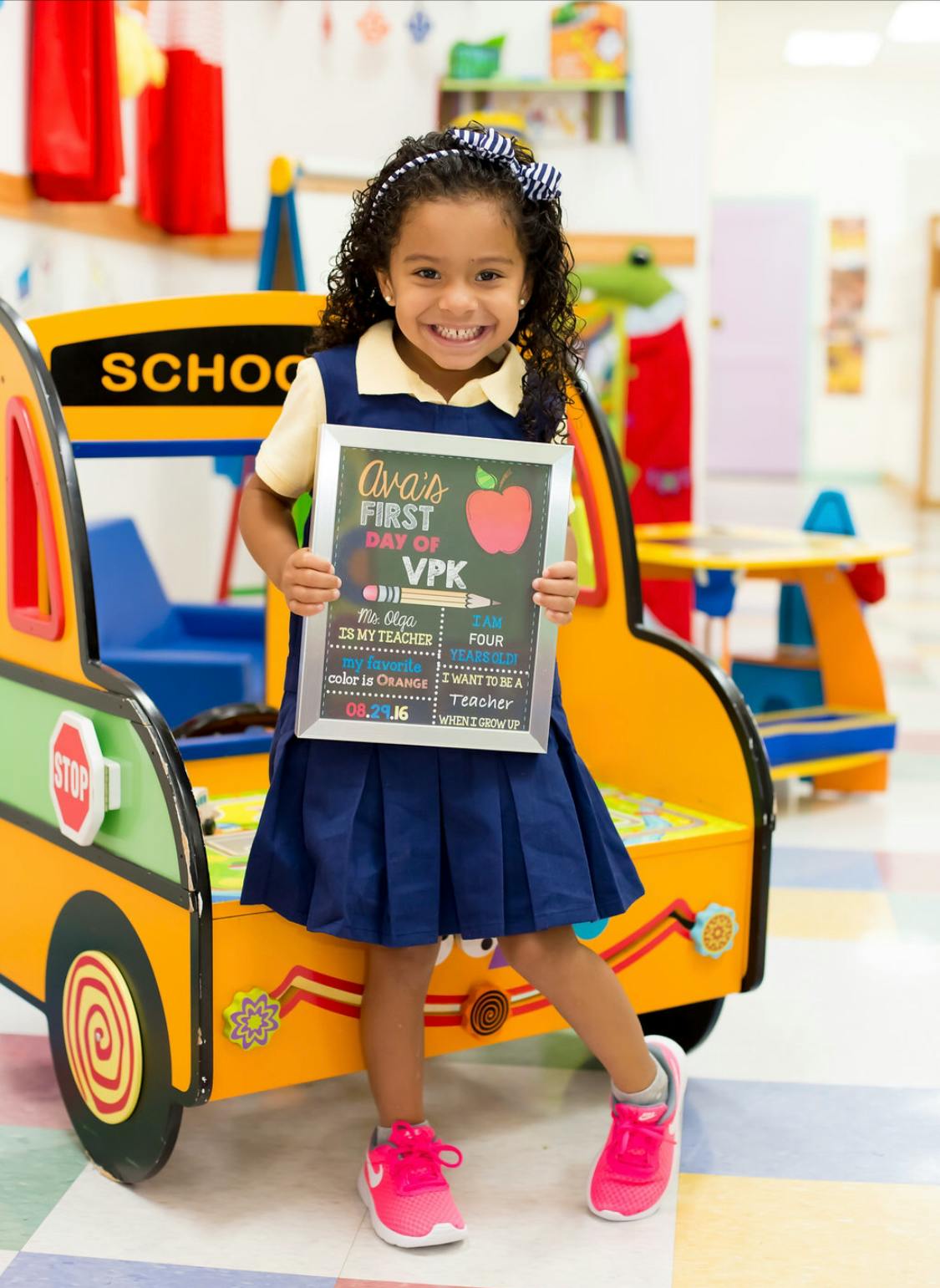 Child holding a sign that reads "Ava's First Day of VPK"