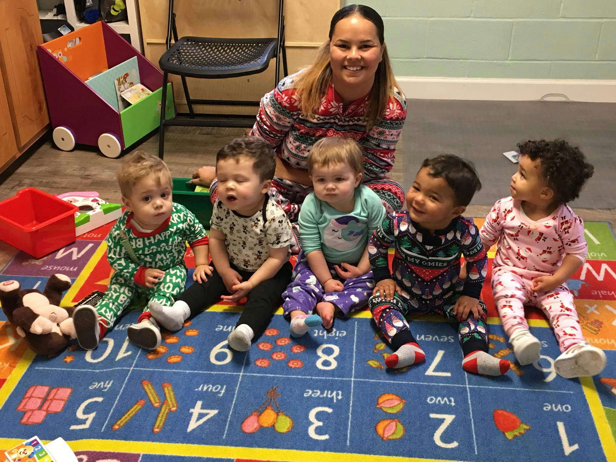 Adult and five children sitting on a colorful rug