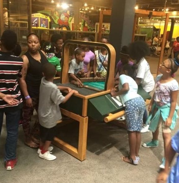 People and children gathered around a game table