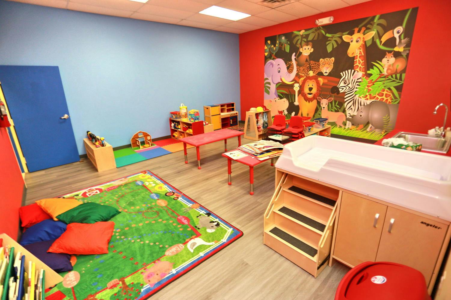 Children's playroom with colorful rug, small tables, and changing station