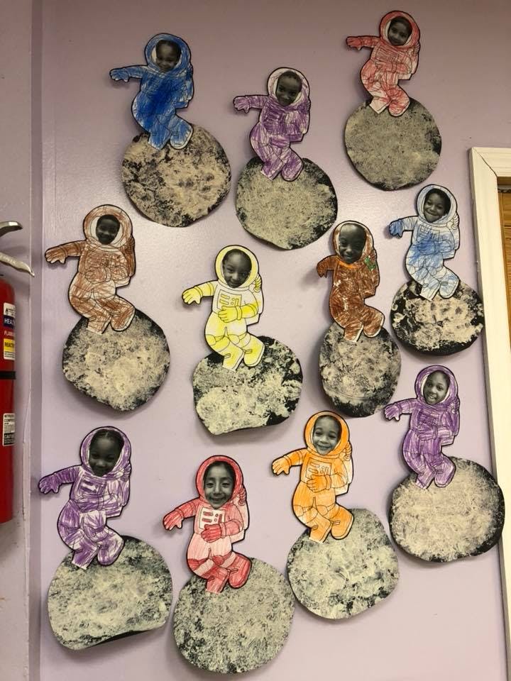 Children's artwork of people in astronaut suits on moon cutouts