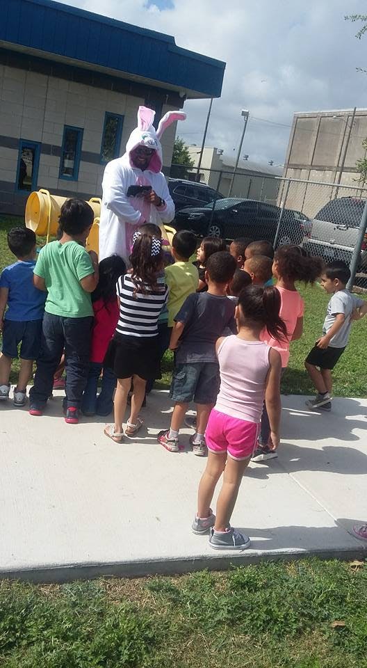 Person in a bunny costume interacting with a group of children outdoors