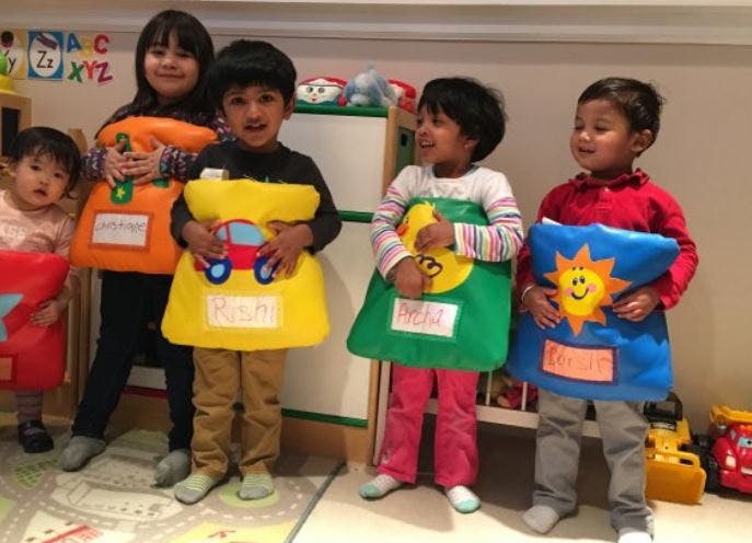 Five children wearing colorful costumes with shapes and designs
