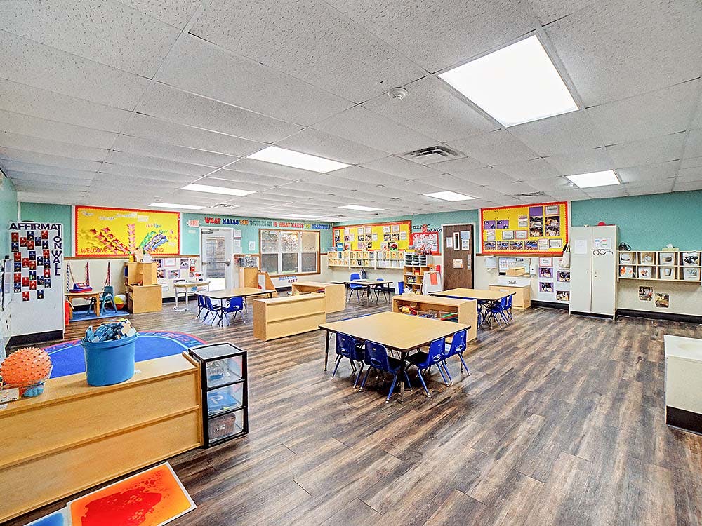 Classroom with small tables and chairs, and bright decorations on the walls