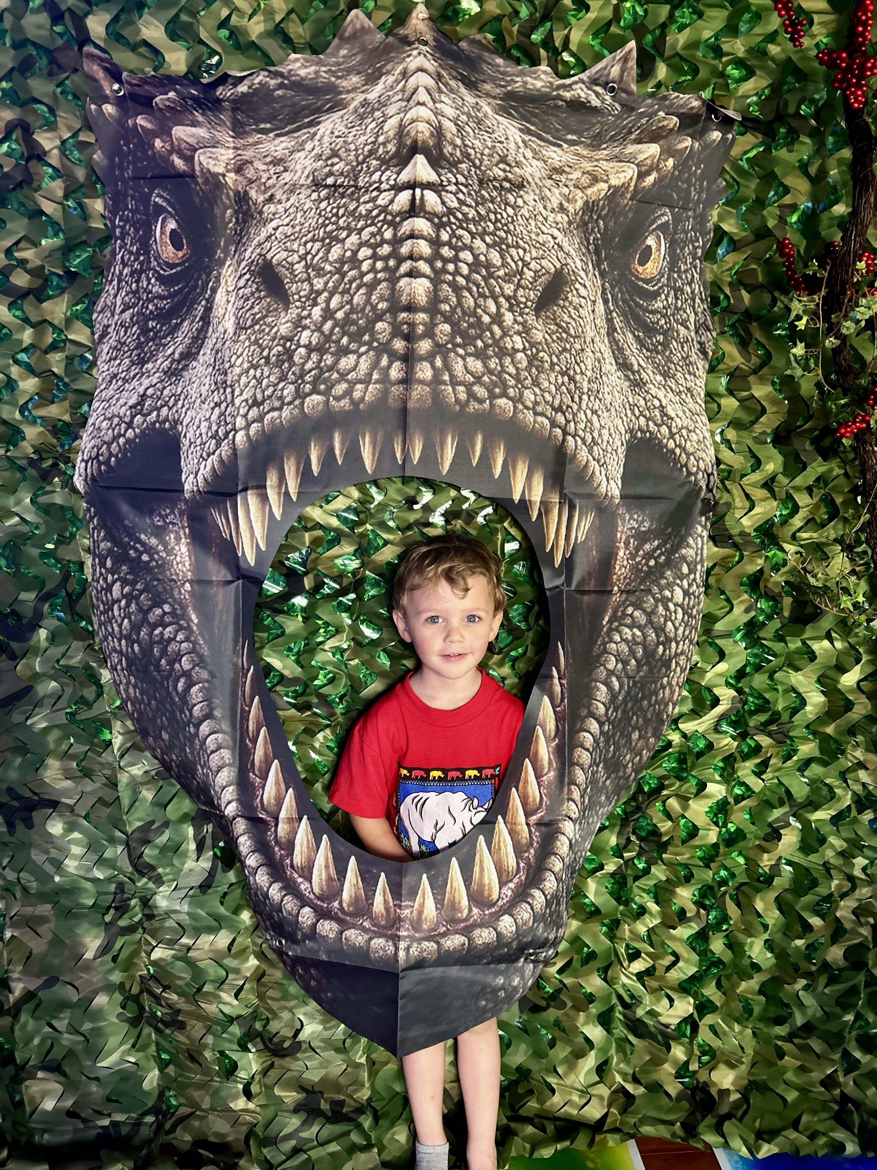 Child peeking through a dinosaur cutout on a jungle-themed background