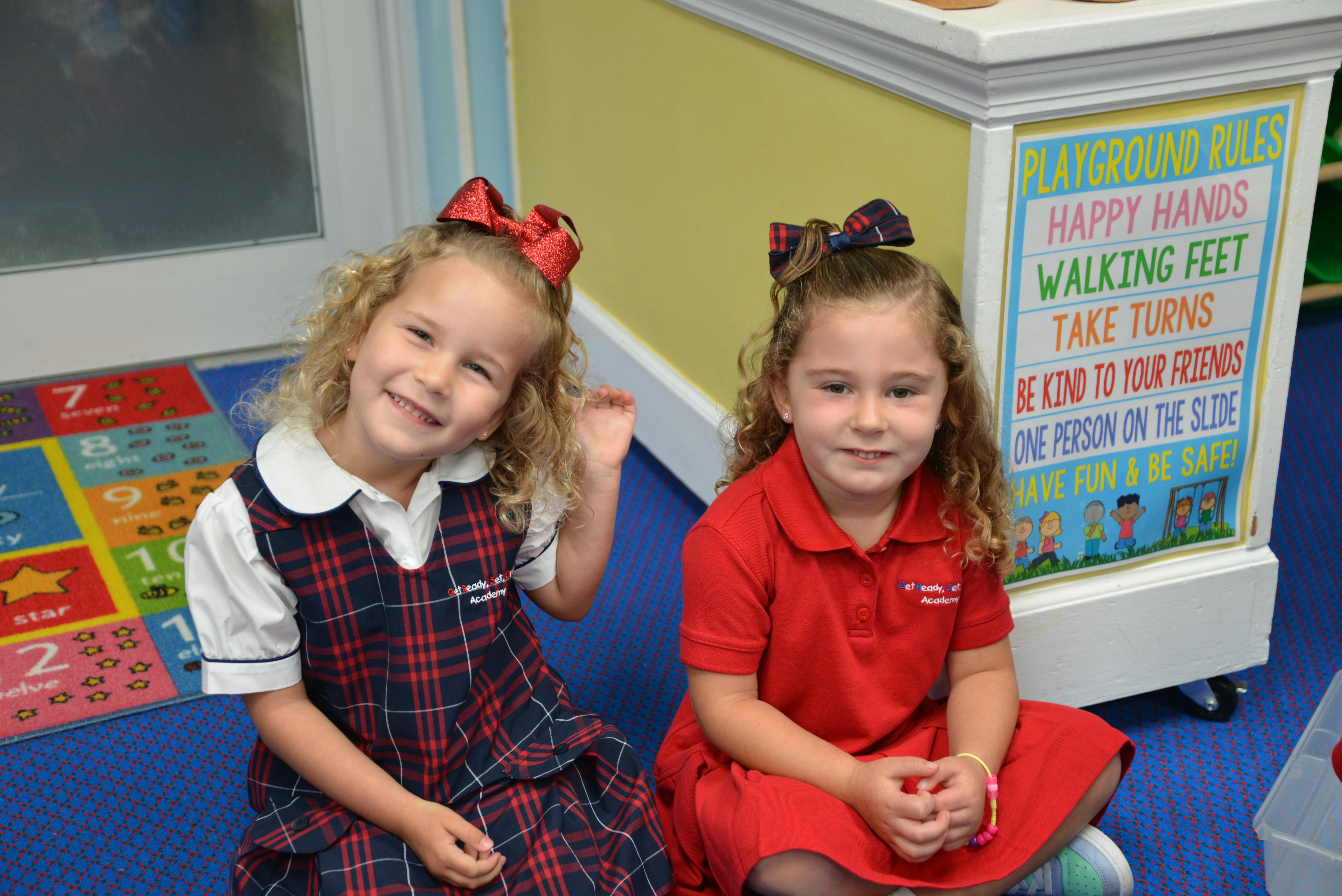 Two children sitting on the floor in a classroom