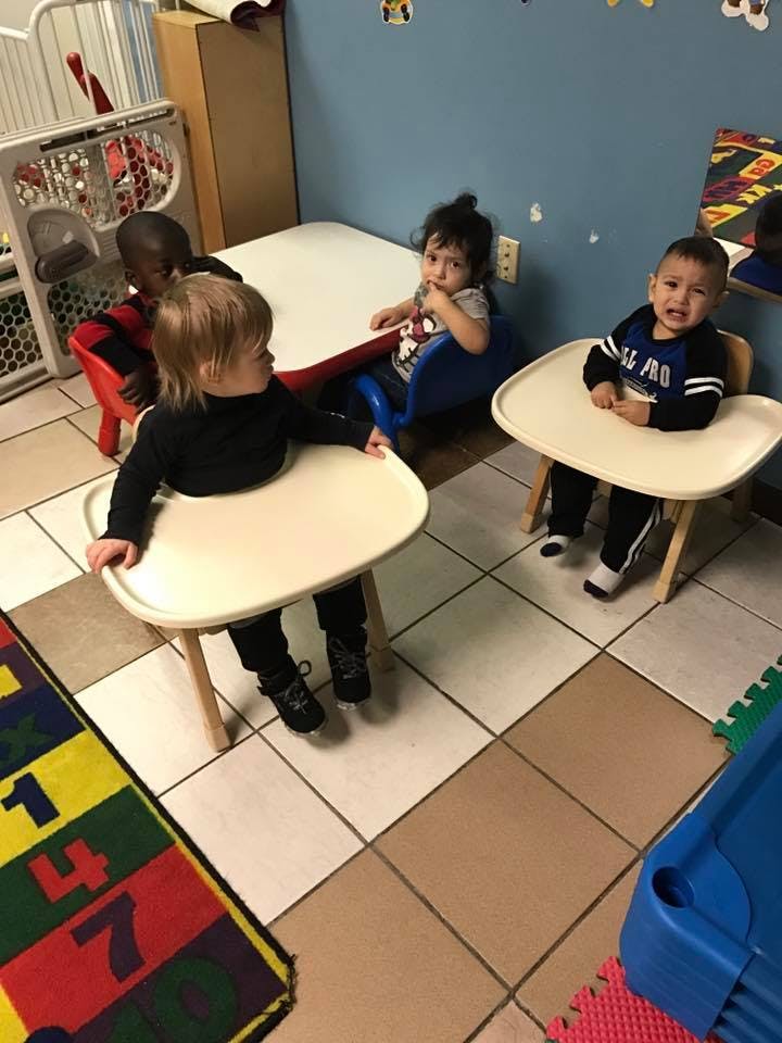 Three children sitting at small tables in a room