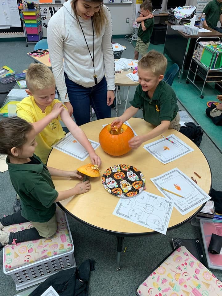 Adult and children carving a pumpkin at a table