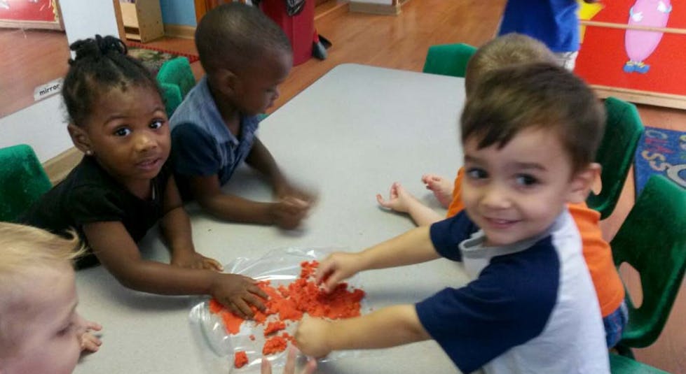 Children at a table playing with orange material