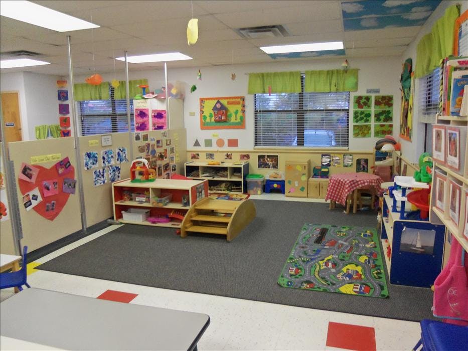 Empty classroom with colorful decorations, play rug, and furniture