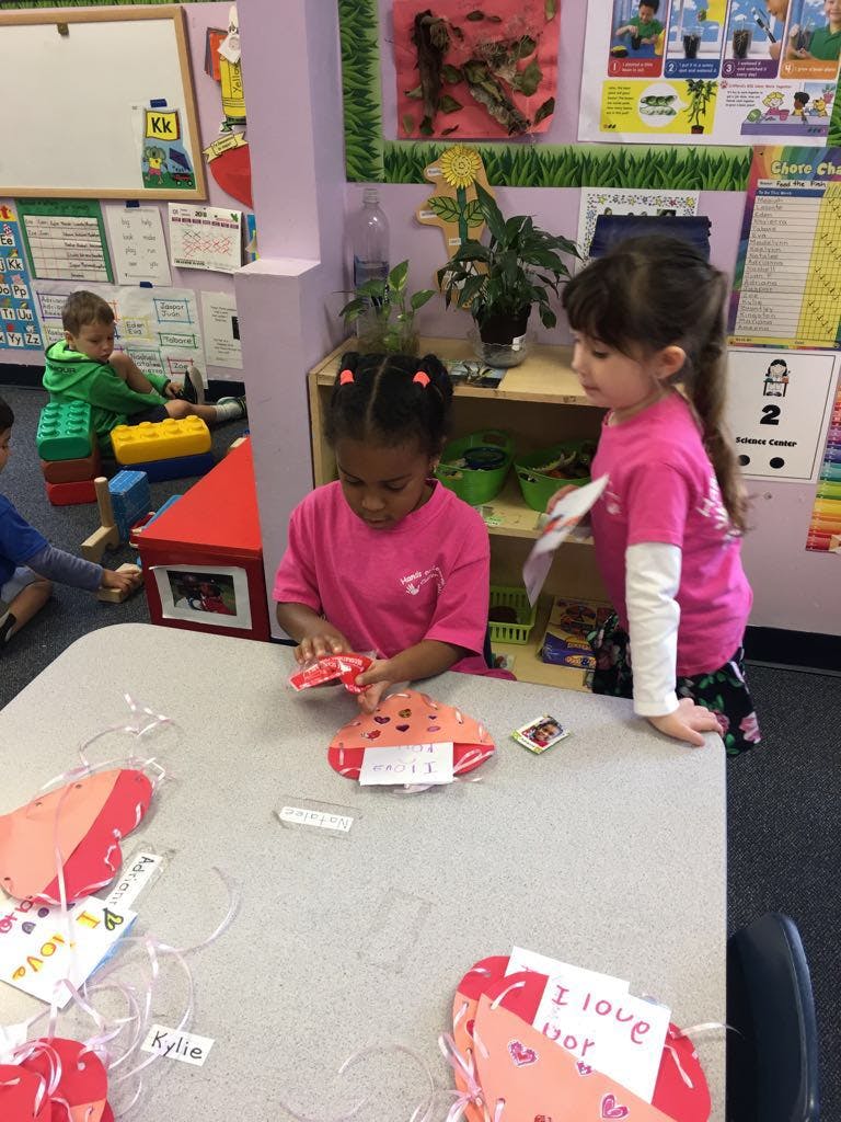 Two children in a classroom making crafts at a table