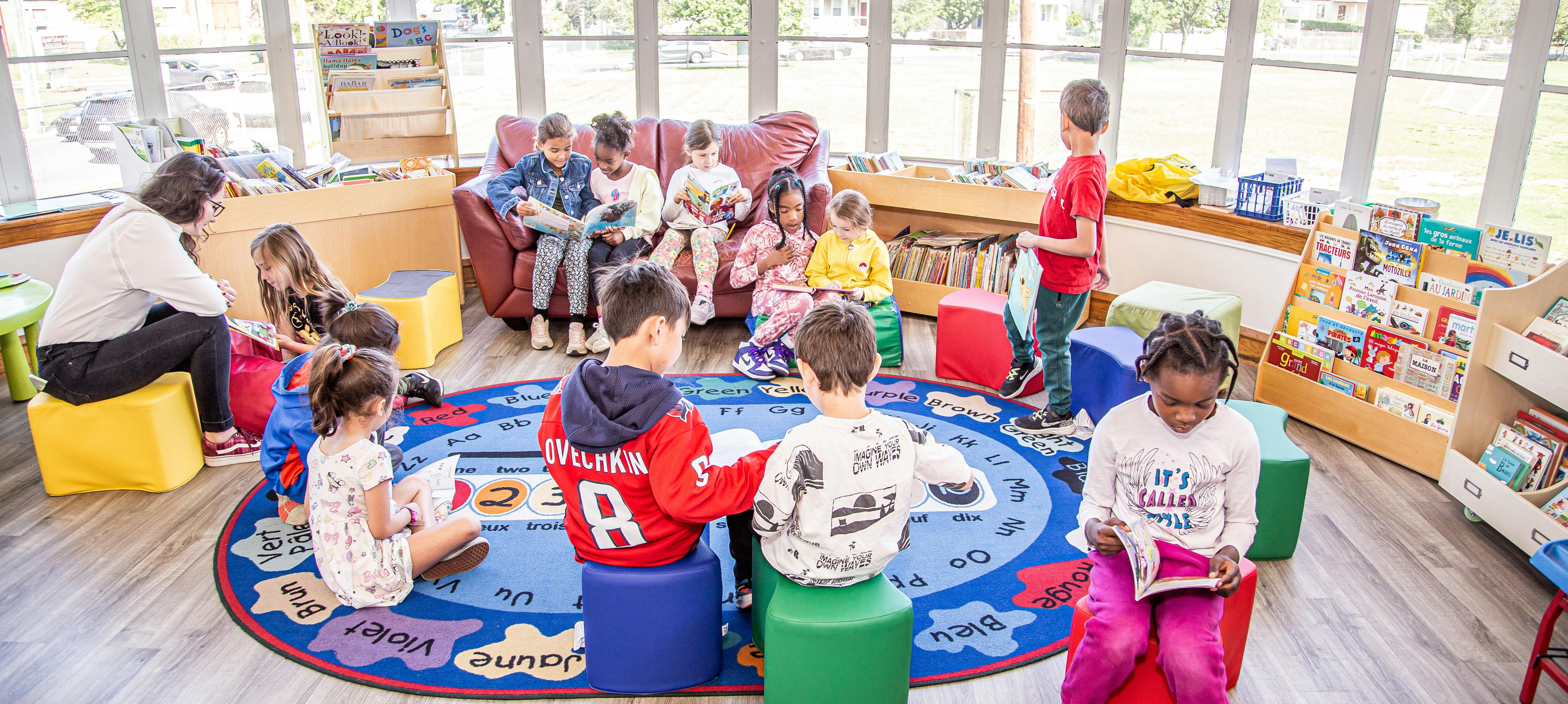 Adults and children sitting in a classroom, some reading books