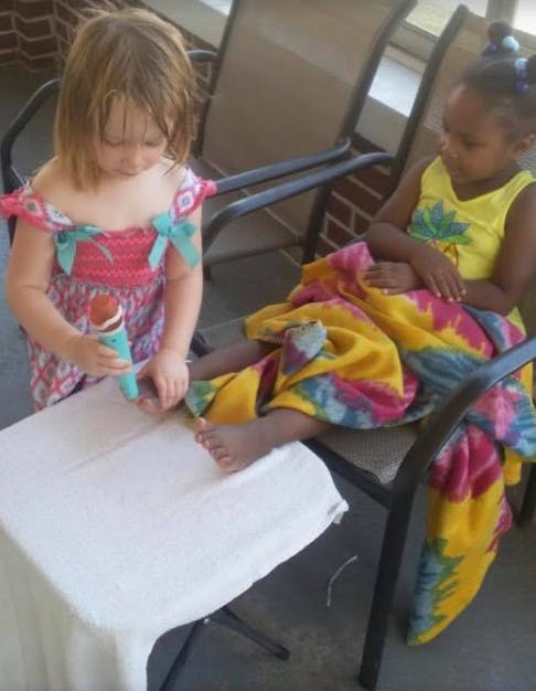 Child holding a toy to another child's foot