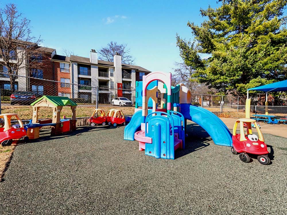 Playground with colorful play structures and toy cars on a rubber ground