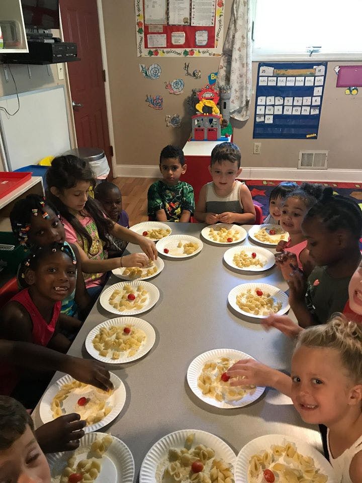 Children sitting at a table with plates of pasta