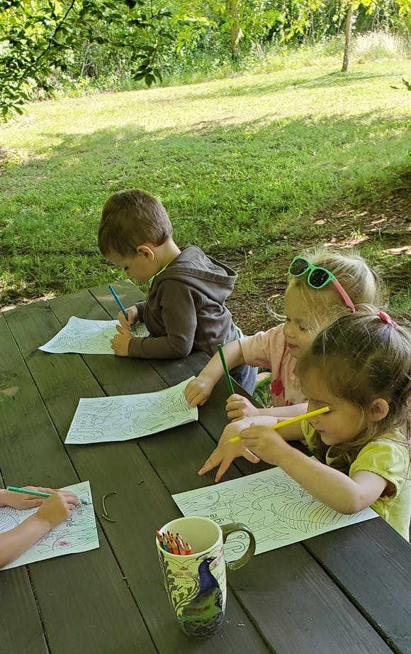 Children coloring at a picnic table outdoors