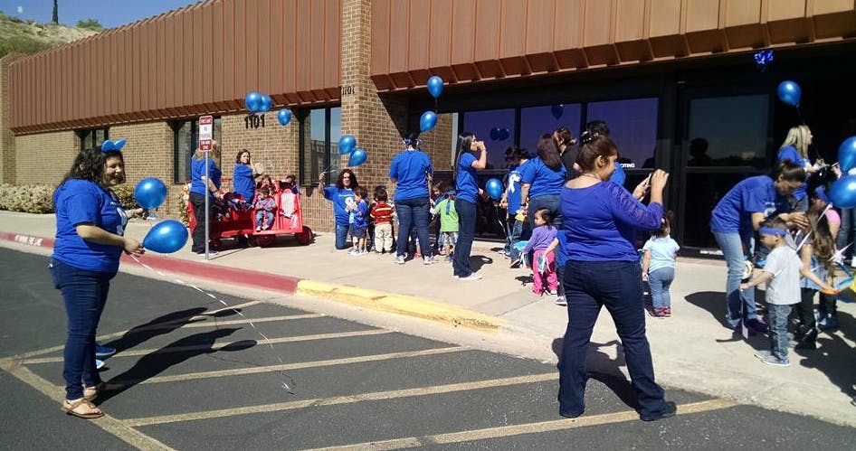 People and children releasing blue balloons outdoors