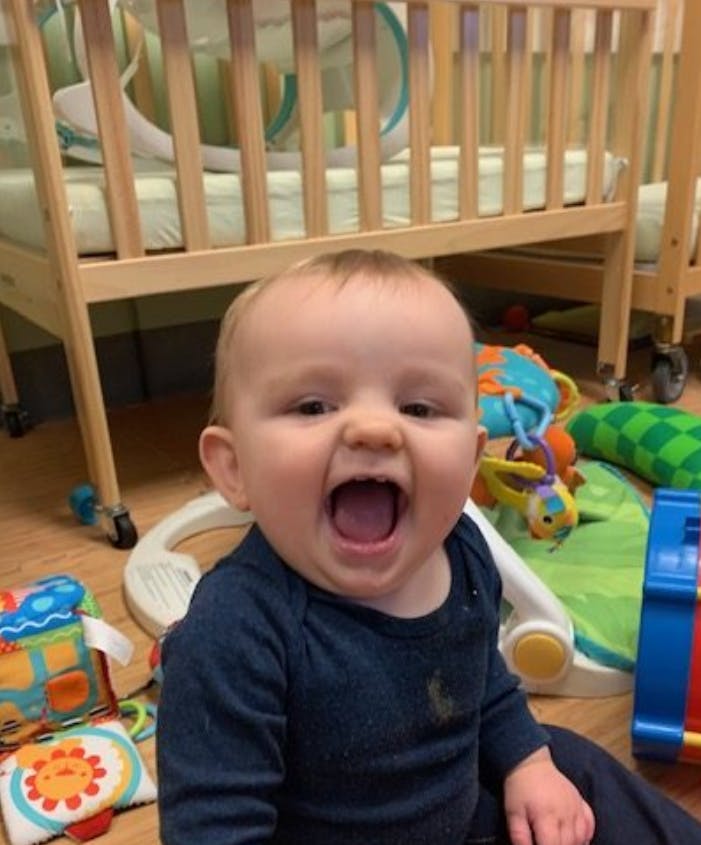 Child with mouth open sitting on floor with toys