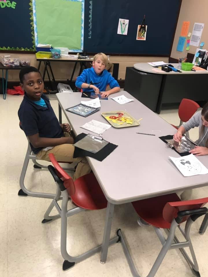 Three children sitting at a table in a classroom