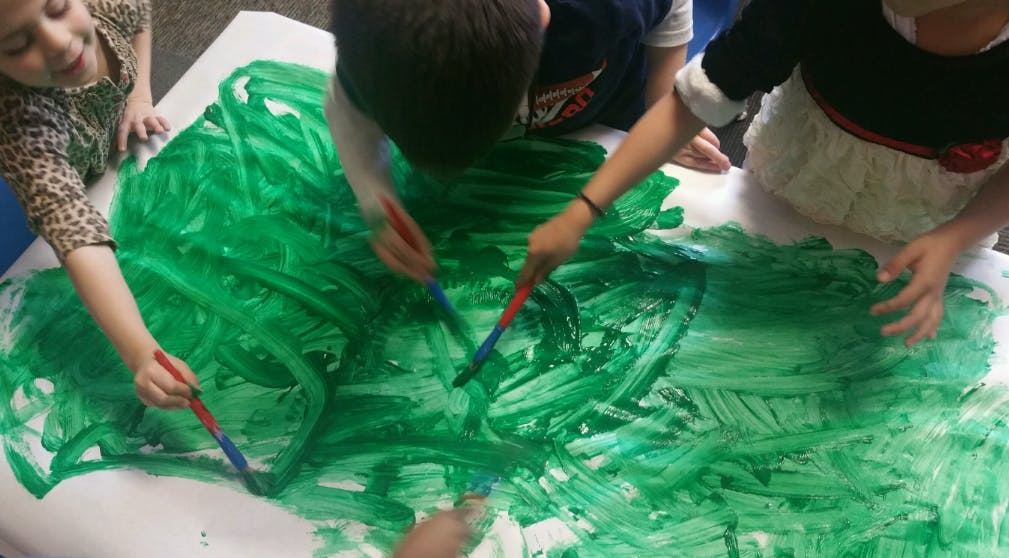 Children painting with green paint