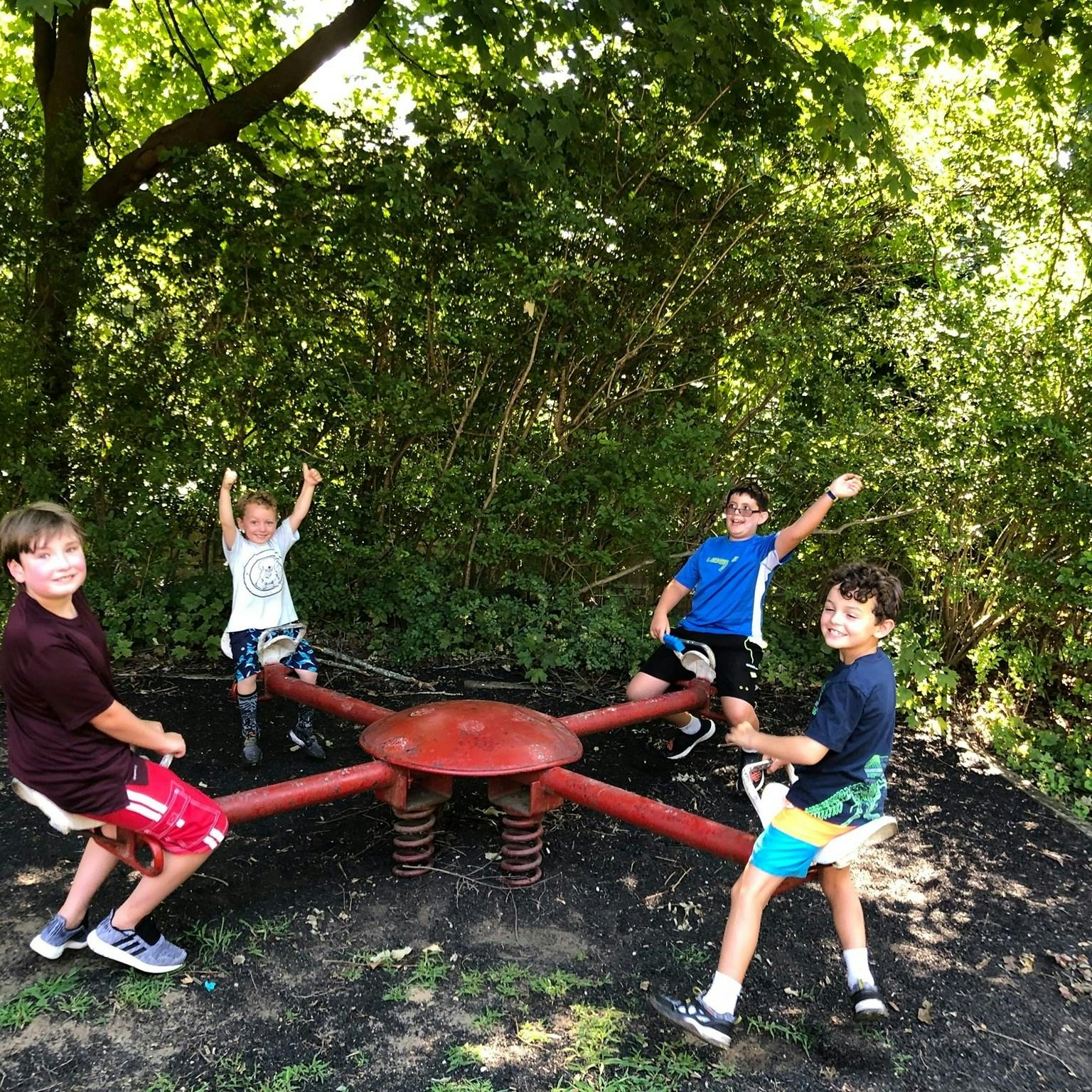 Four children on a red merry-go-round in a park