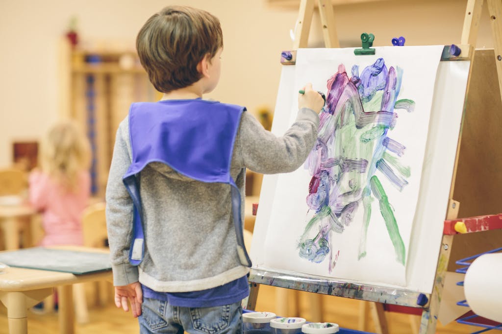 Child painting on an easel in a classroom