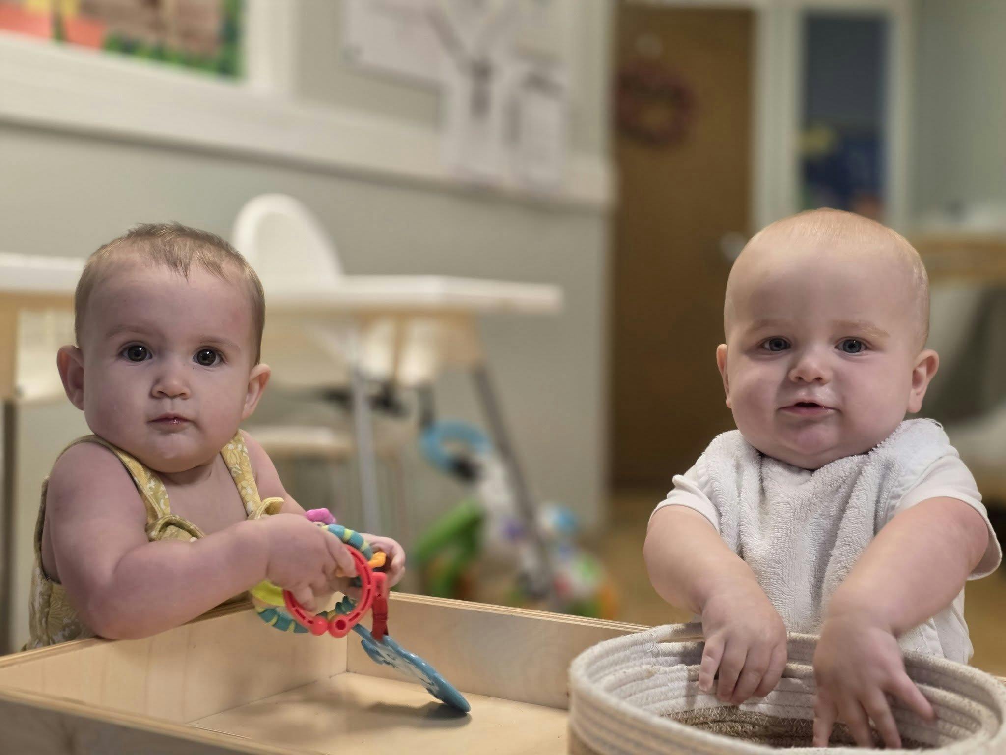 Two babies playing with toys in a classroom
