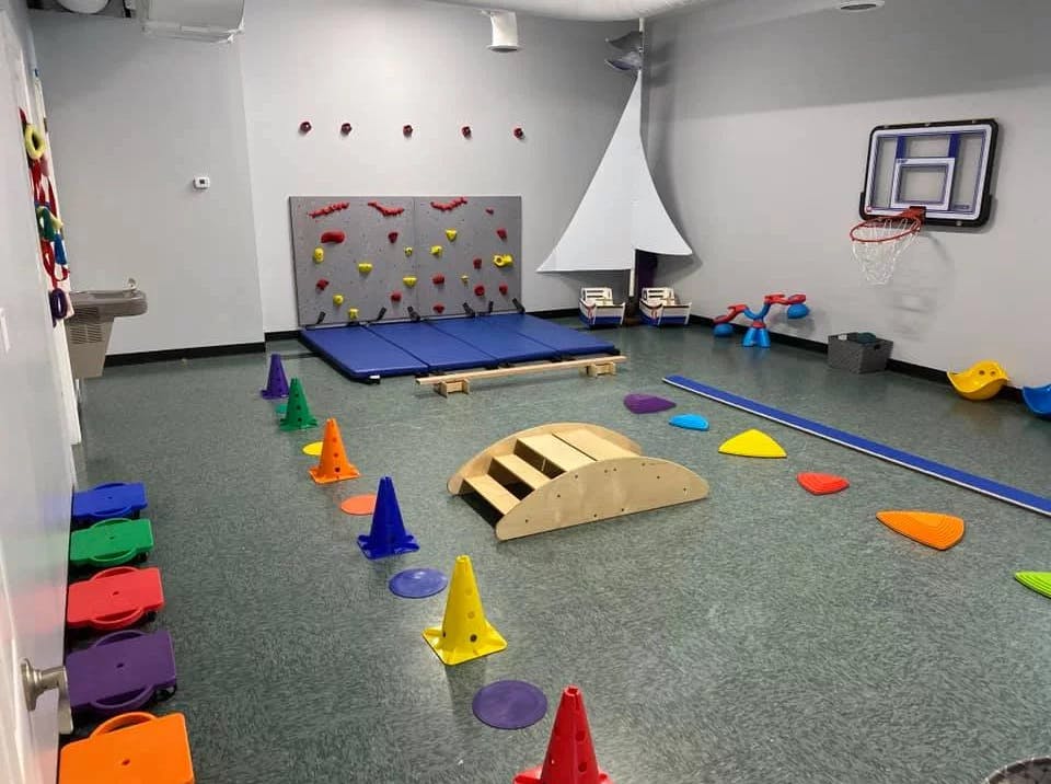 Indoor play area with climbing wall, balance beam, and colorful cones