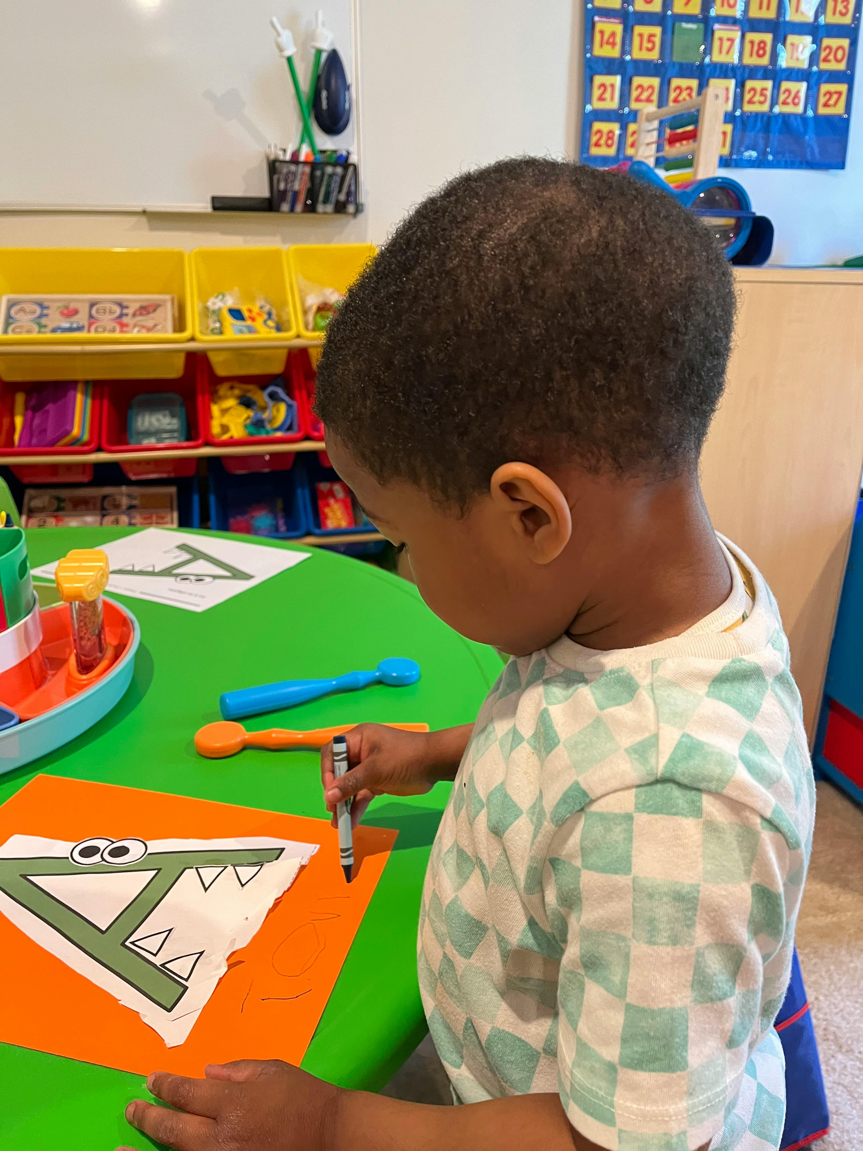 Child coloring a letter A craft in a classroom