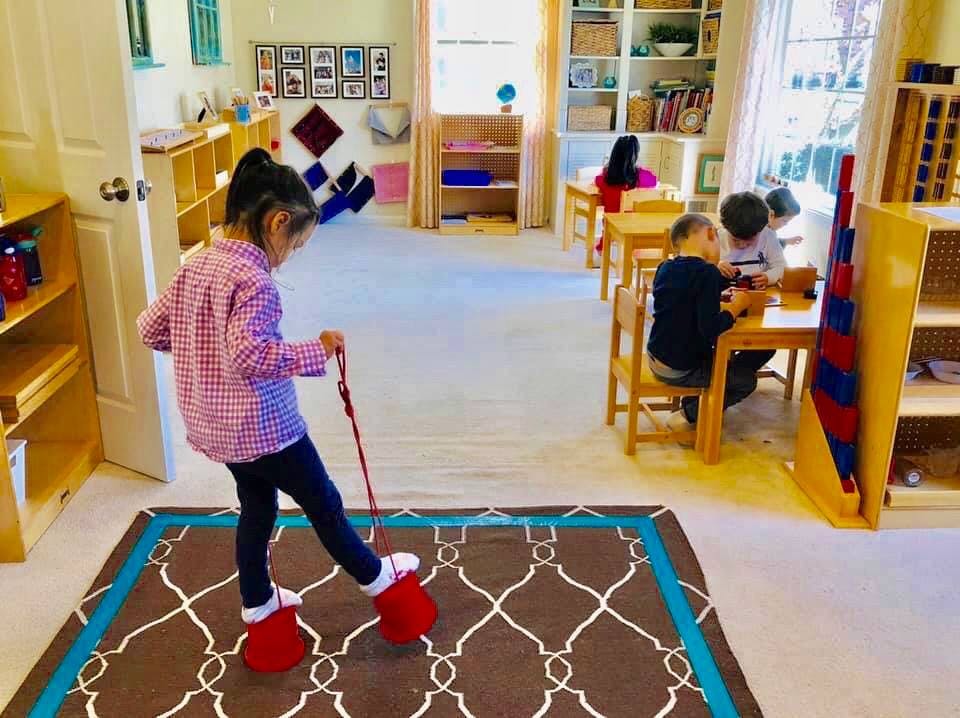 Child walking on a rug with red foot coverings in a classroom
