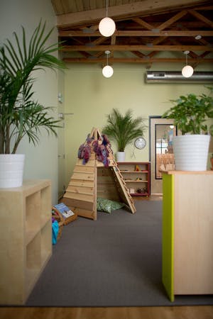 Indoor play area with a wooden teepee and plants