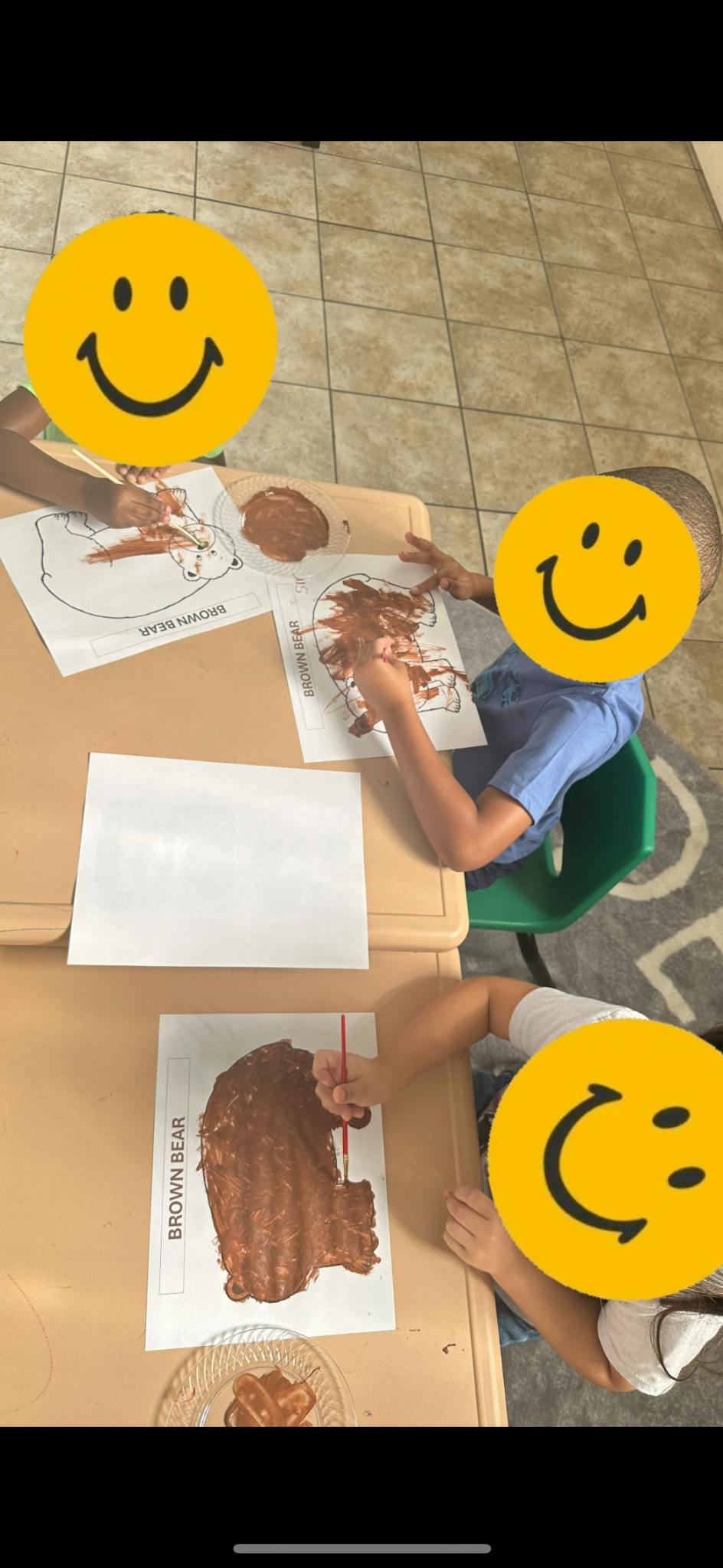 Children painting brown bear worksheets at a table