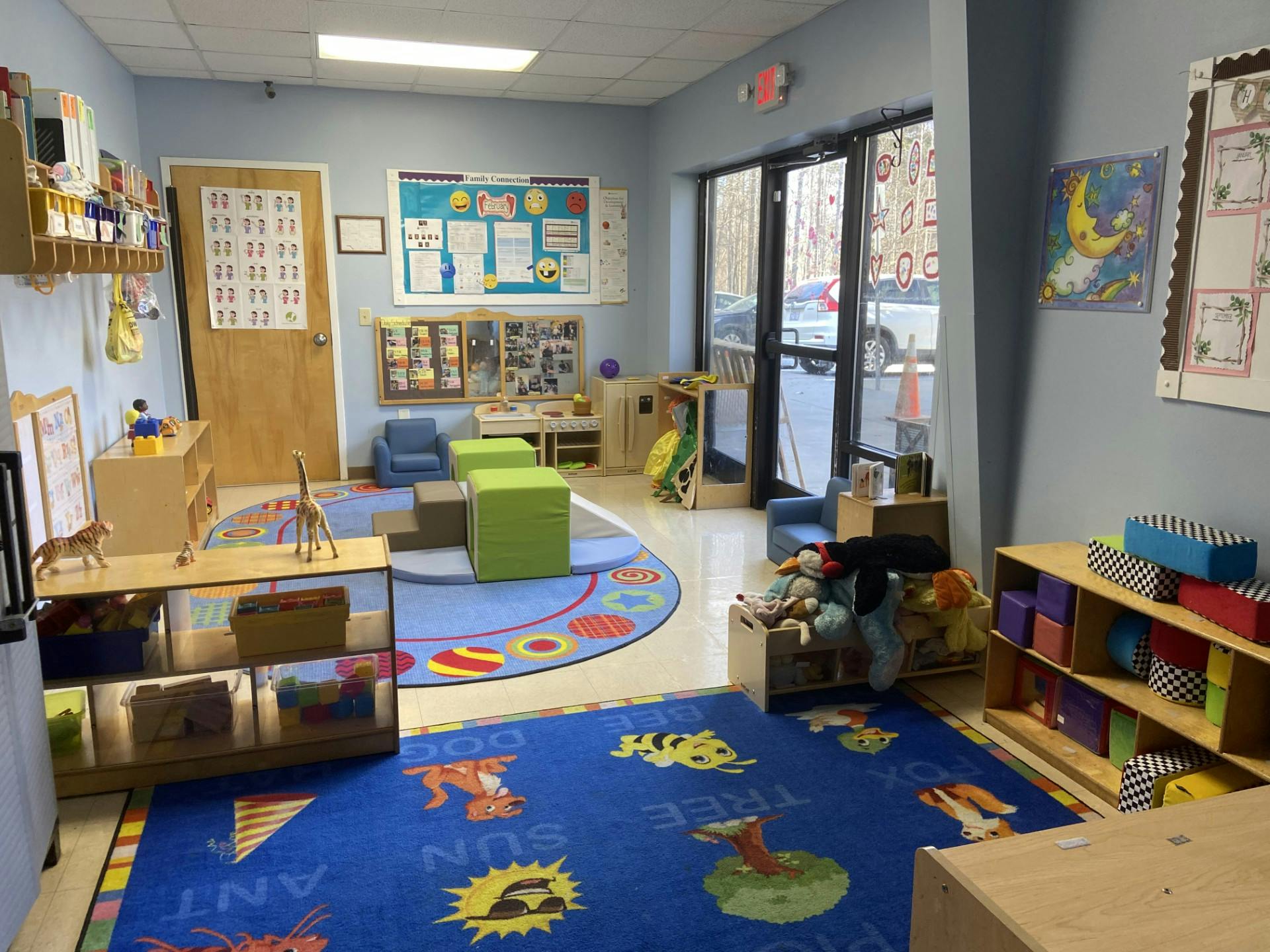 Colorful classroom with play rugs, furniture, toys, and bulletin boards