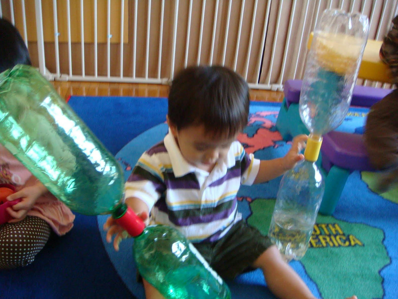 Child playing with plastic bottles filled with water and other materials