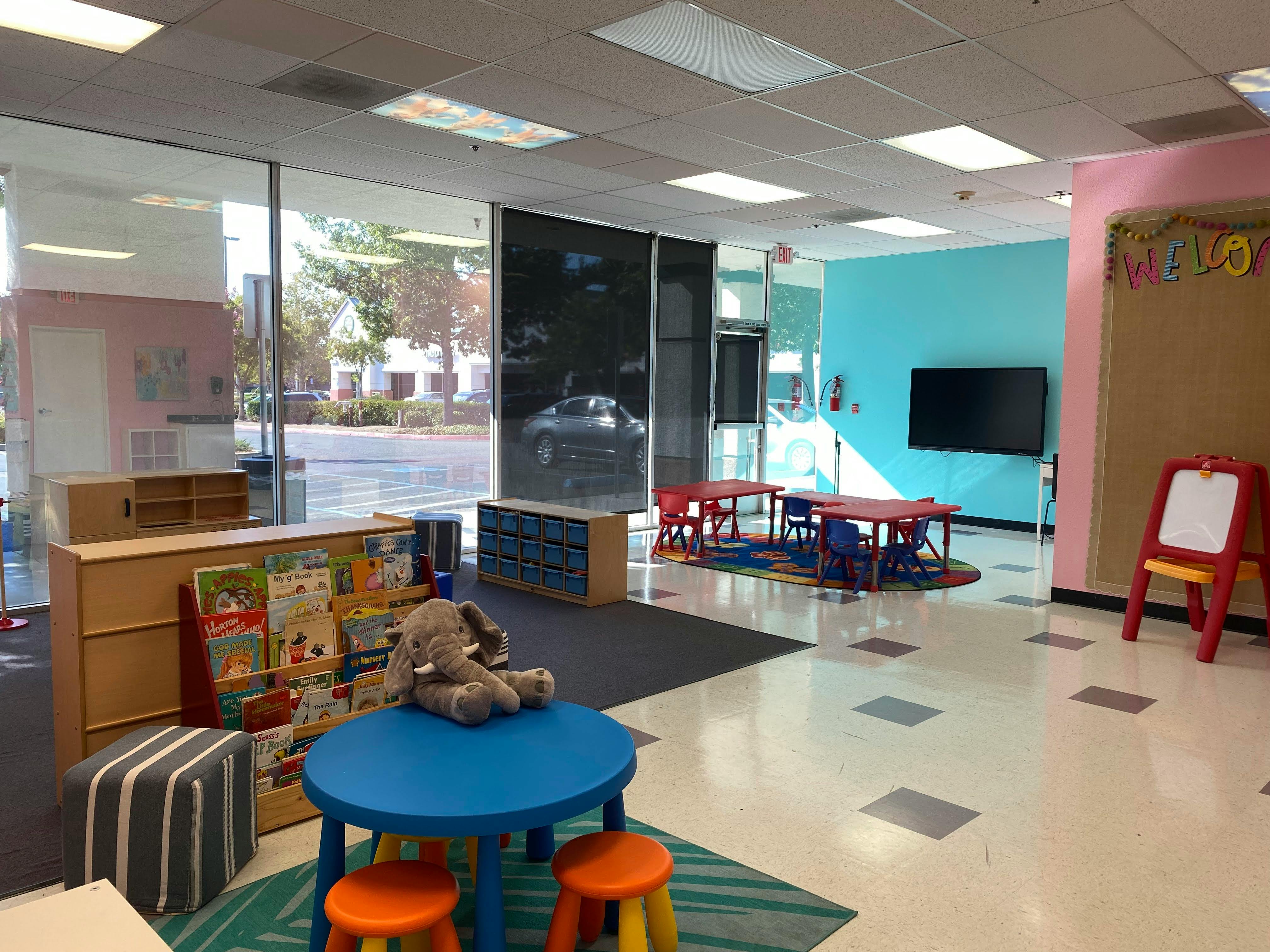 Children's play area with tables, chairs, and a bookshelf