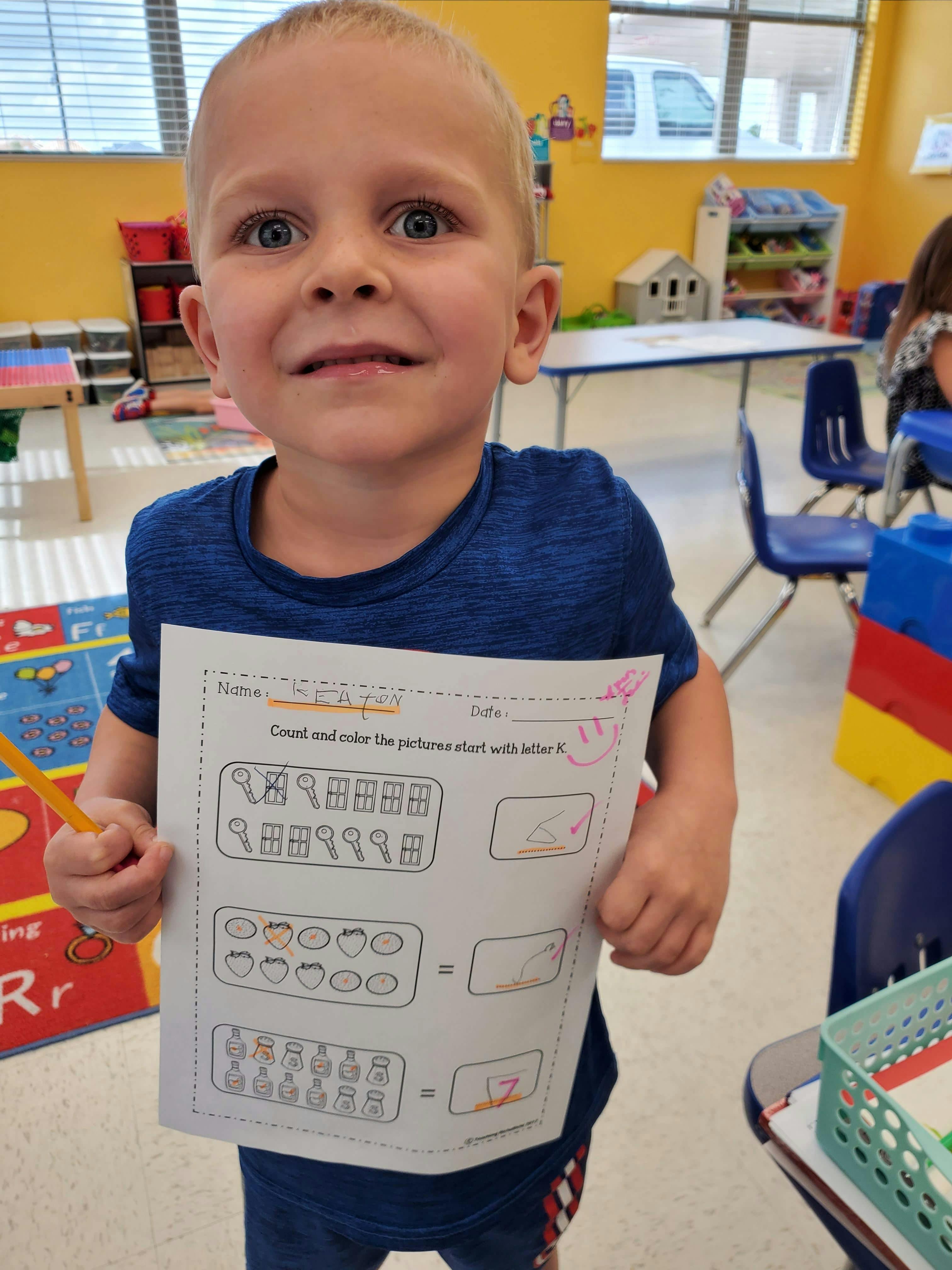 Child holding up a worksheet in a classroom