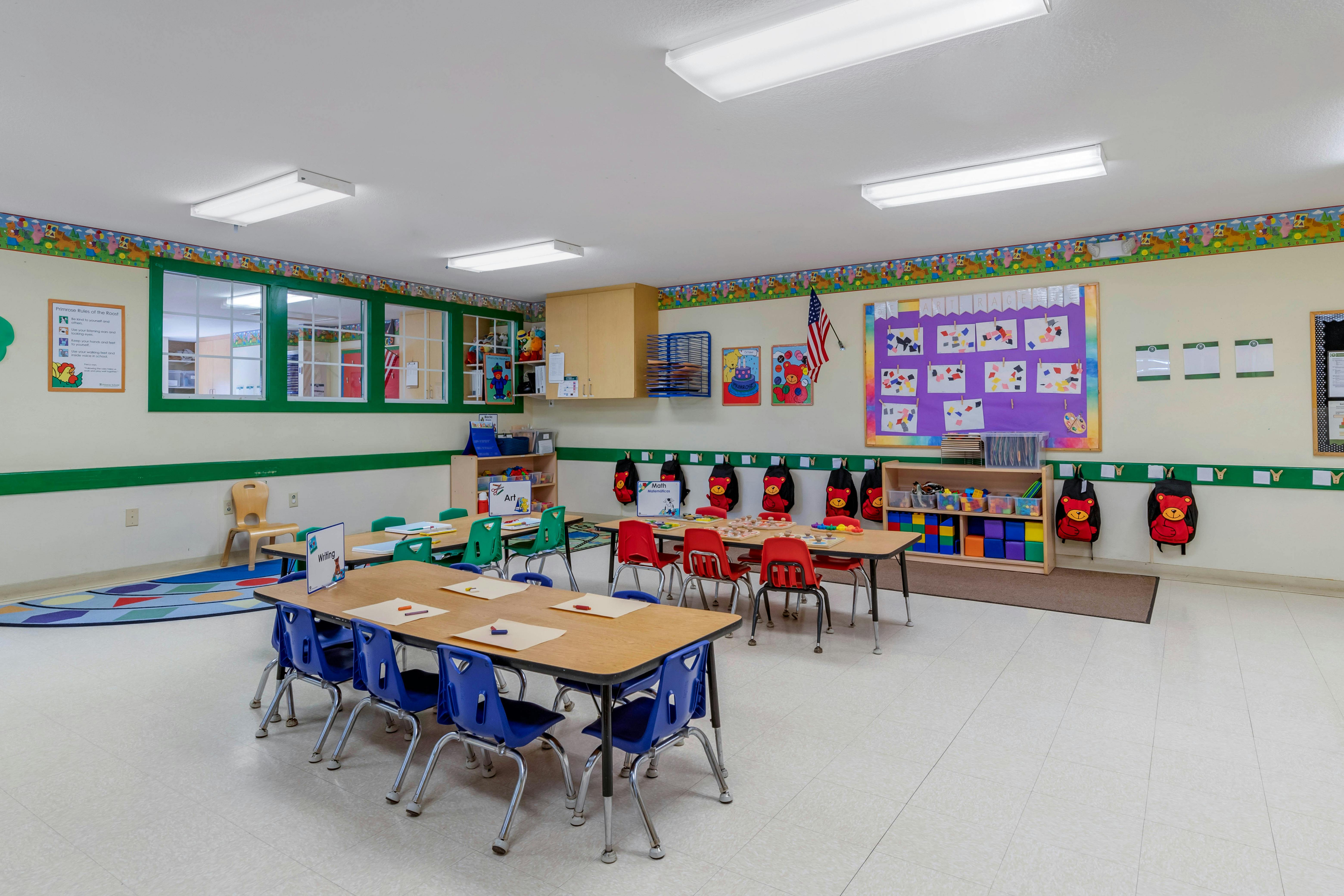 Classroom with small tables and chairs, wall decorations, and a sign titled "Primrose Rules of the Roost"