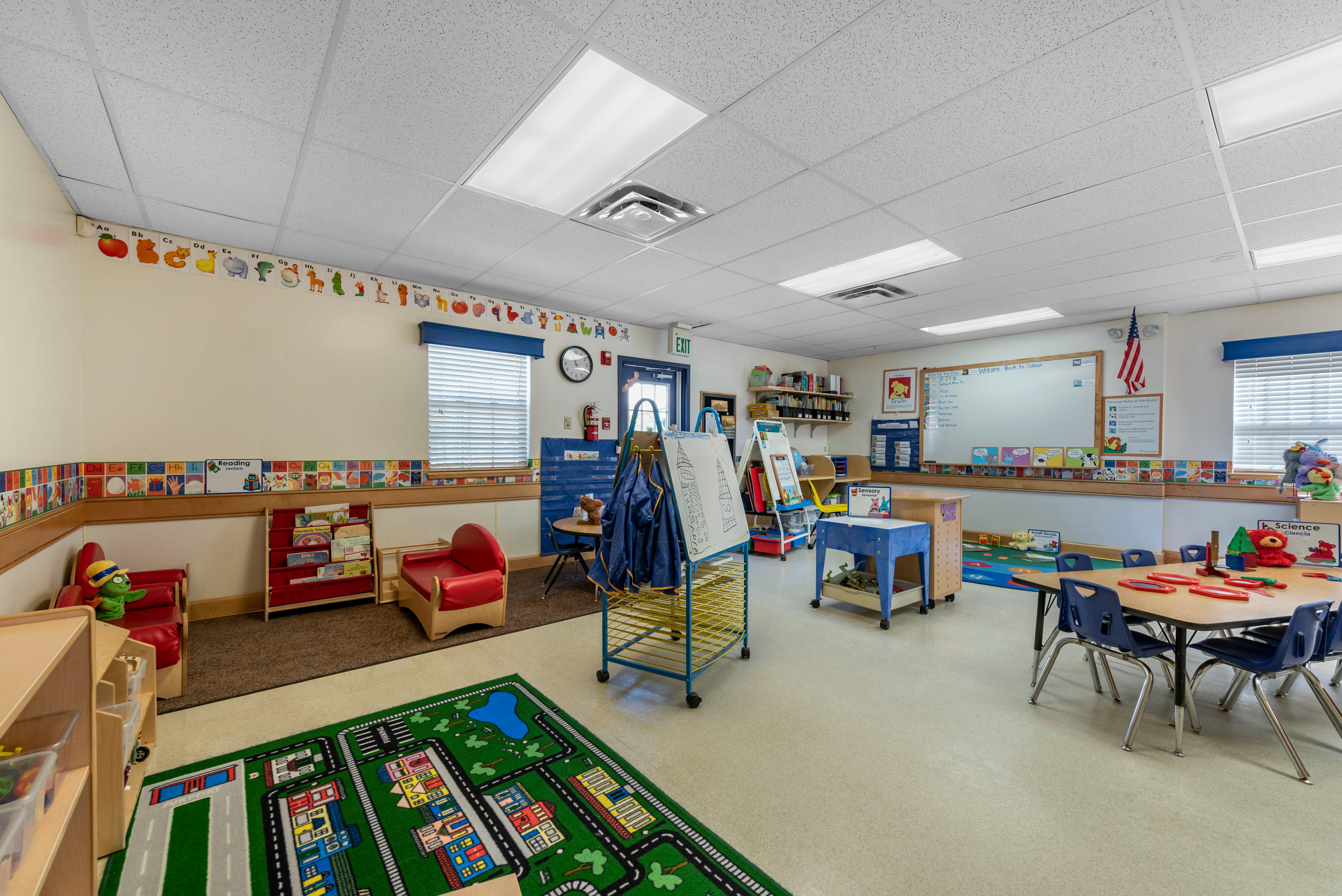 Classroom with small tables, chairs, bookshelves, and alphabet decorations