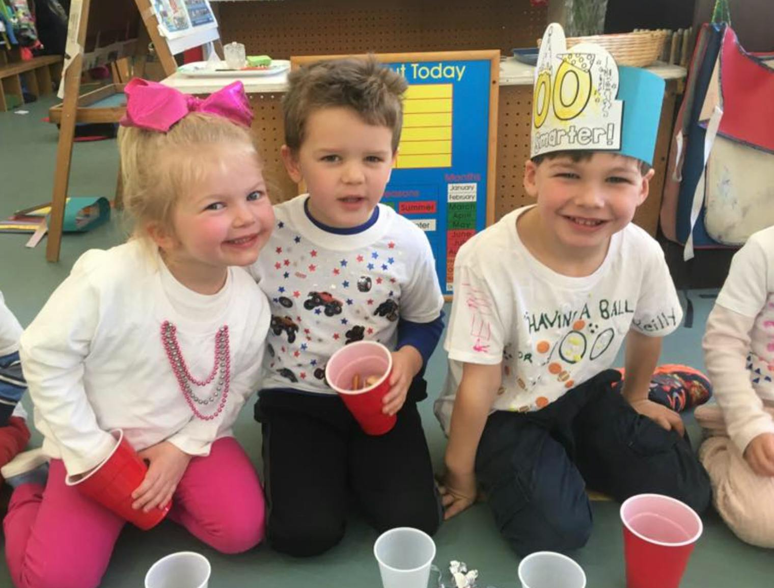 Three children kneeling with red cups