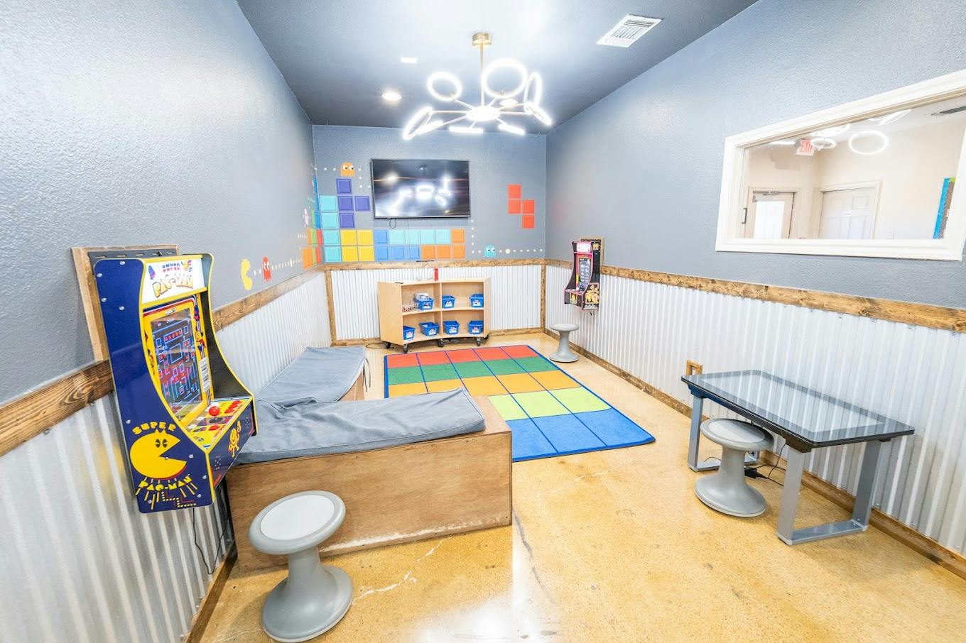 Game room with arcade machines a play rug and seating