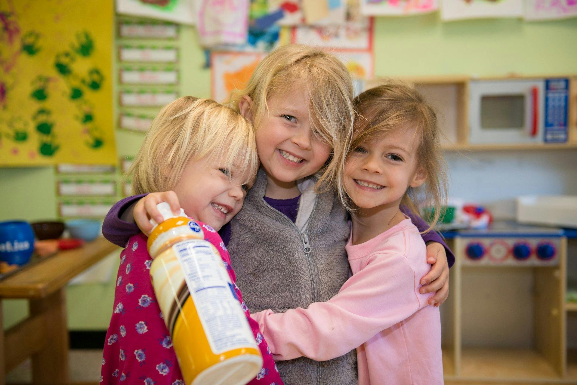 Three children embracing in a classroom
