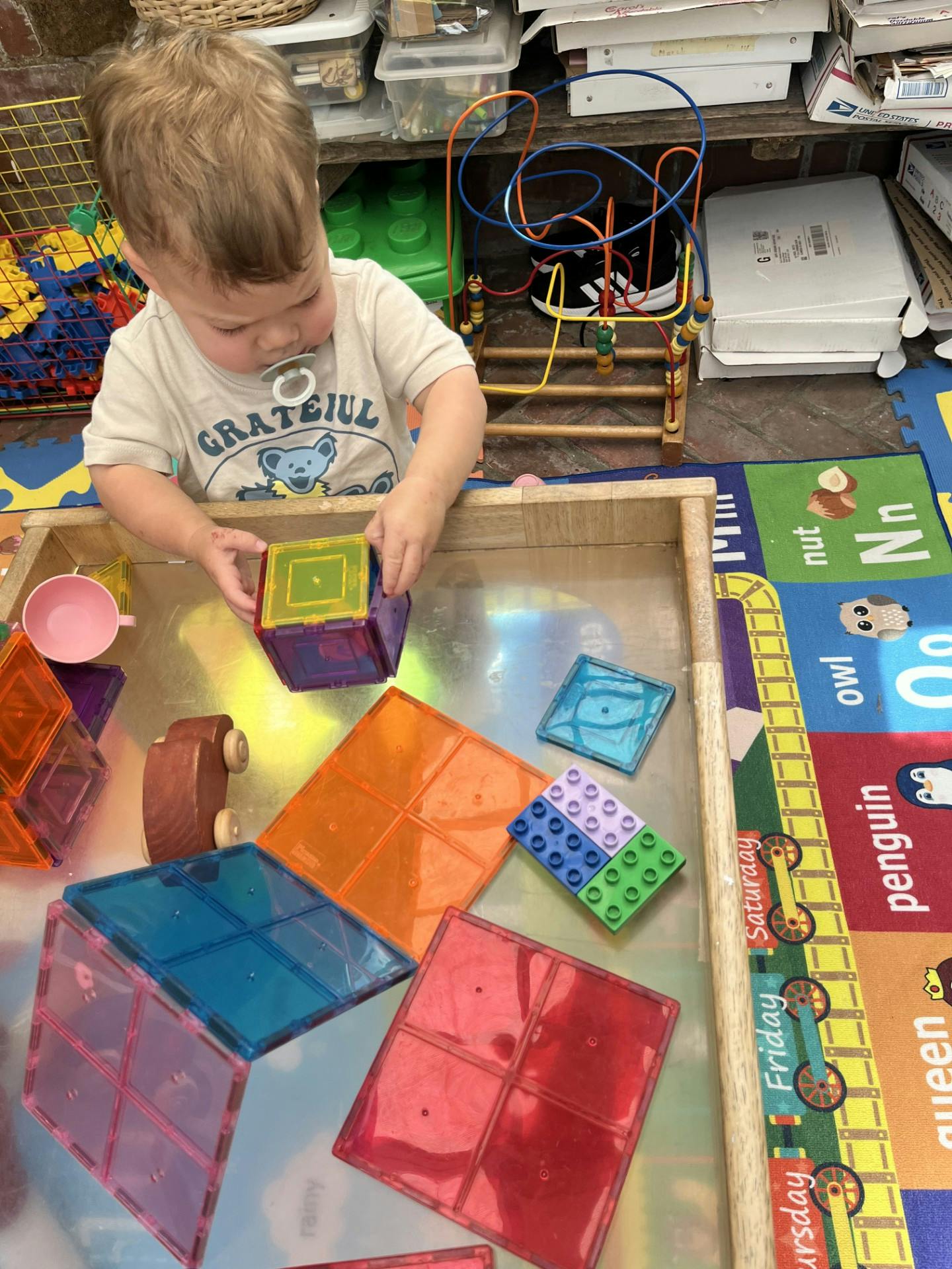 Child building with colorful magnetic tiles on a play table