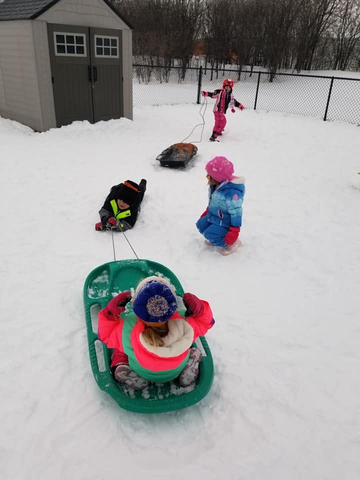 Children playing in snow with sleds