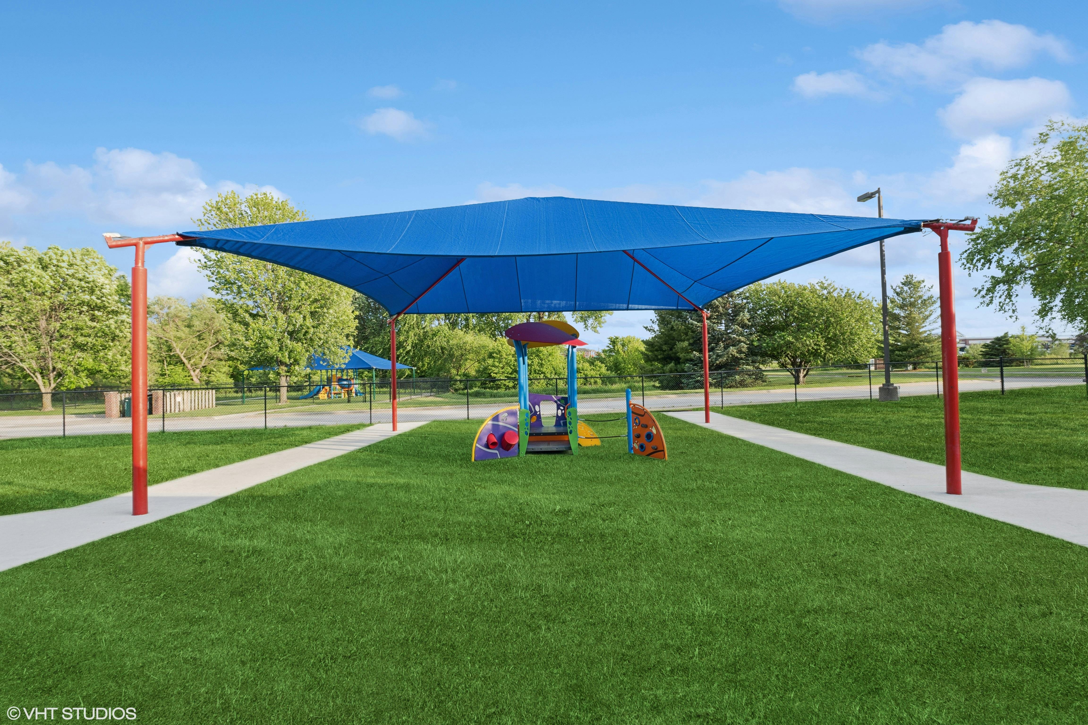 Playground with a blue shade structure over play equipment