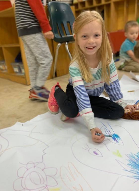 Child drawing on large paper with a marker