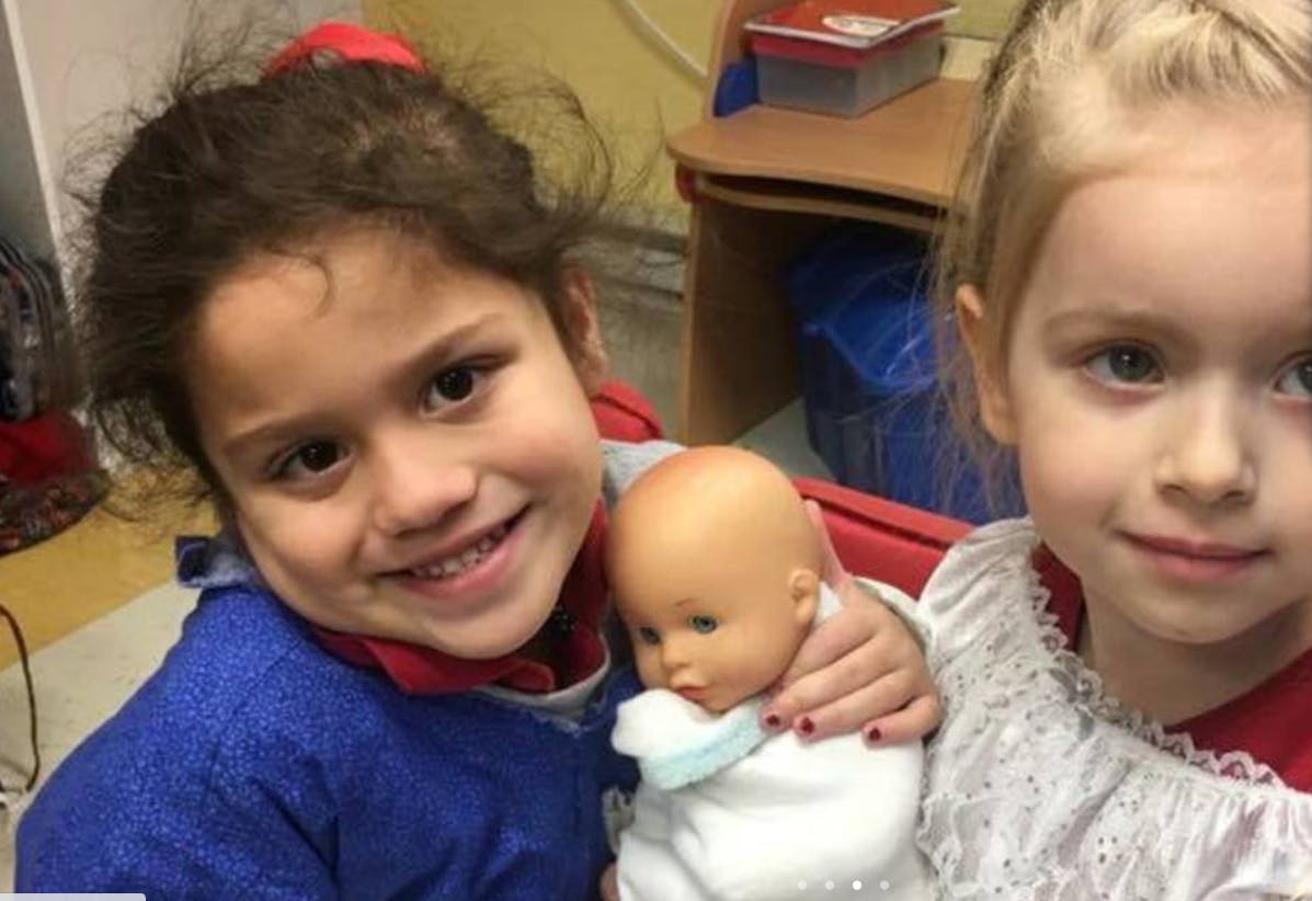 Two children holding a baby doll