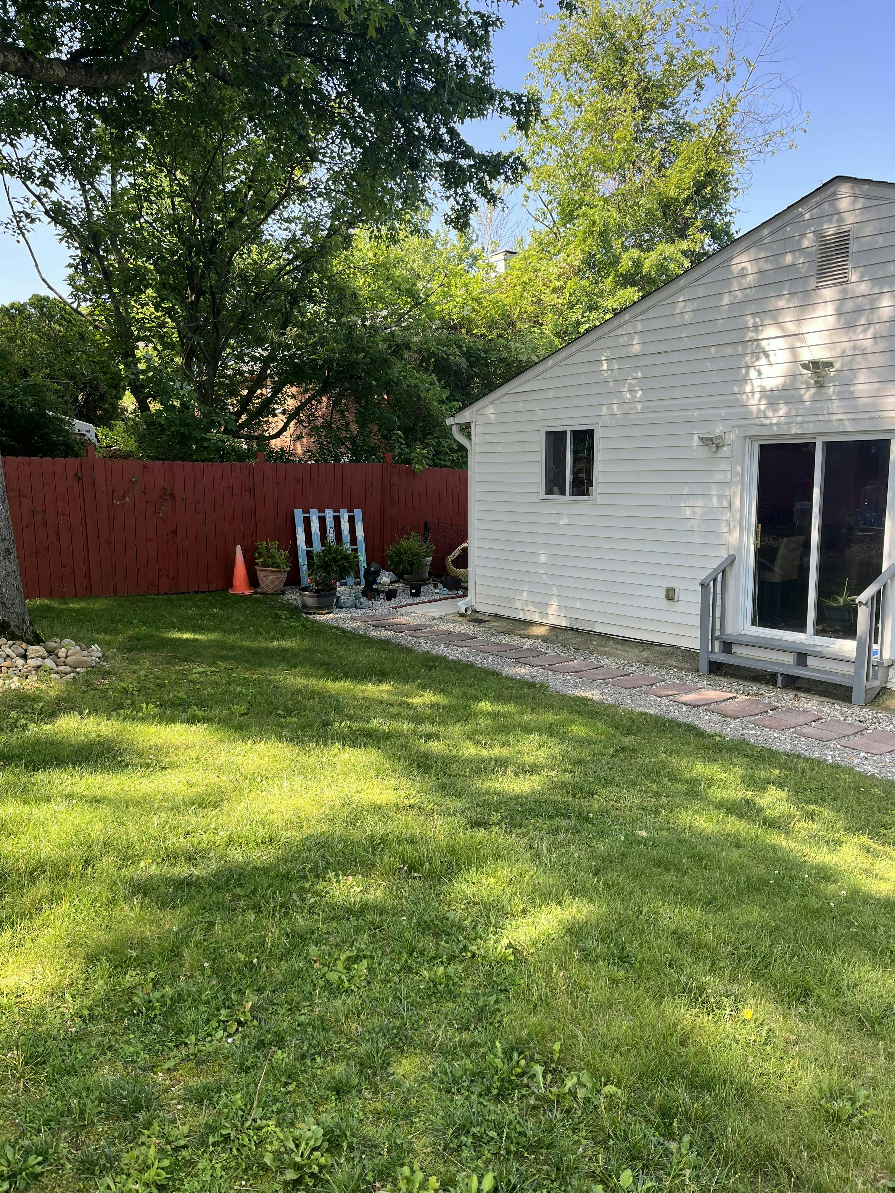 Backyard with a white house, red fence, and green grass