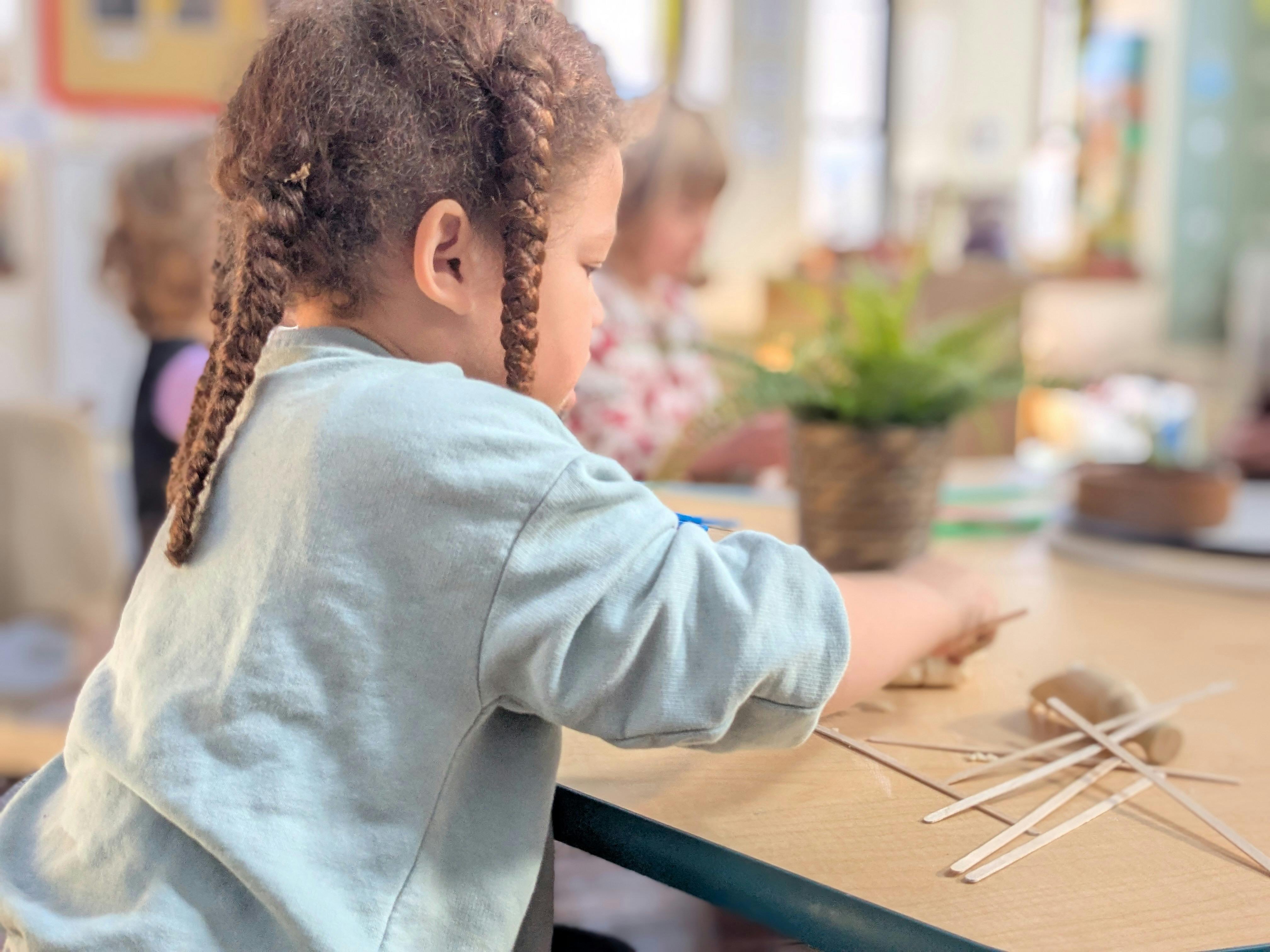 Child with braided hair working on a craft project at a table